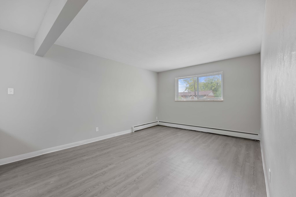 Empty room with a window and a wooden floor.