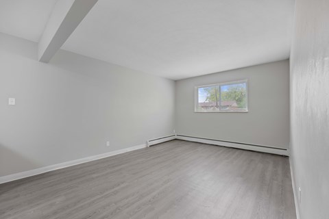 Empty room with a window and a wooden floor.