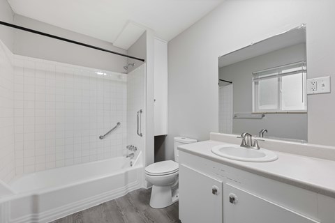 A white bathroom with a toilet, sink, and bathtub.