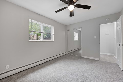 A room with a ceiling fan and a window with blinds.