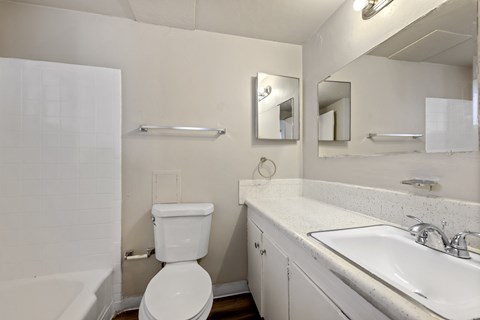A white toilet sits in a bathroom next to a sink and mirror.