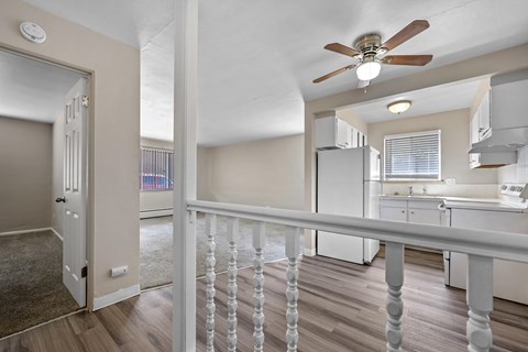 A room with a ceiling fan and a balcony with a railing.