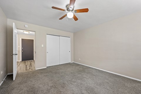 A room with a ceiling fan and carpeted floor.