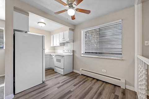 A kitchen with a white refrigerator and a ceiling fan.