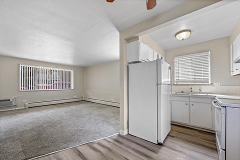 A kitchen with white appliances and wooden floors.