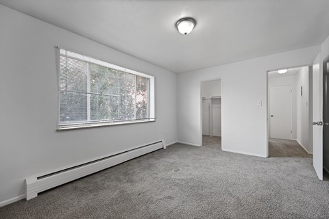 A room with a window and a carpeted floor.