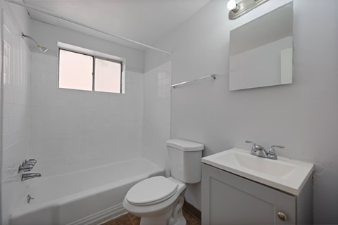 A white bathroom with a toilet, sink, and bathtub.