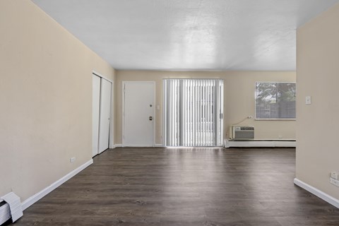 A room with a white ceiling, a window with blinds, and a wooden floor.