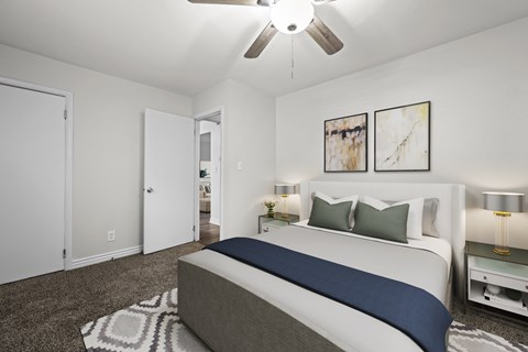 A bedroom with a bed, nightstands, and a ceiling fan.
