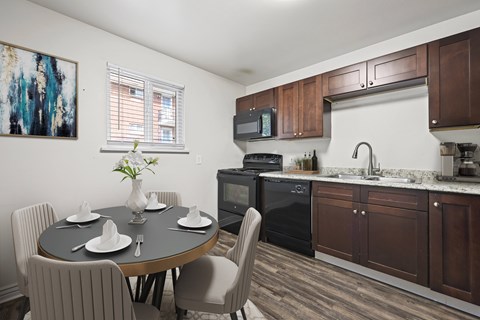A kitchen with a table set for four with a painting on the wall.