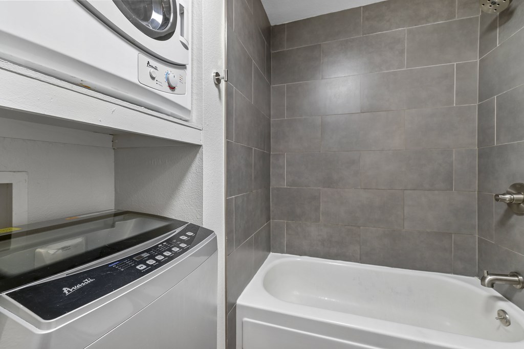 A white washing machine and dryer in a small bathroom.