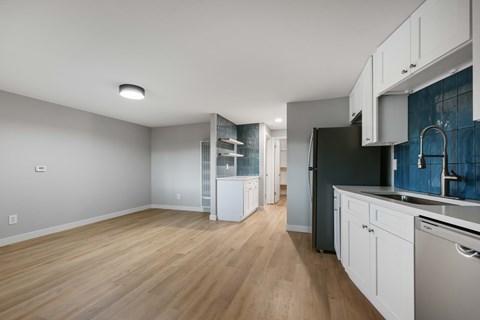 A kitchen with white cabinets and a black fridge.