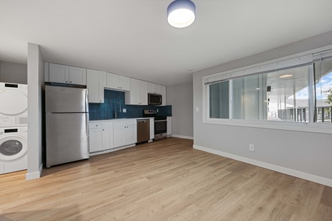 A modern kitchen with wooden floors and stainless steel appliances.
