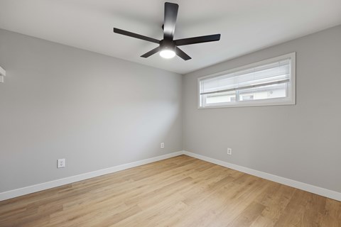 A room with a ceiling fan and a window.