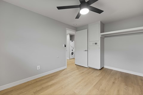 A room with a ceiling fan and a door leading to another room.