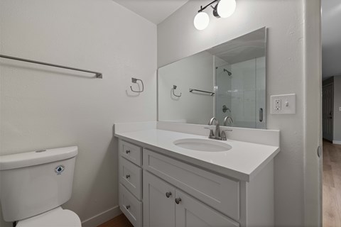 A white bathroom with a toilet, sink, and mirror.