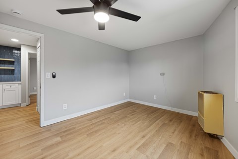 A room with a ceiling fan and a gold object on the floor.