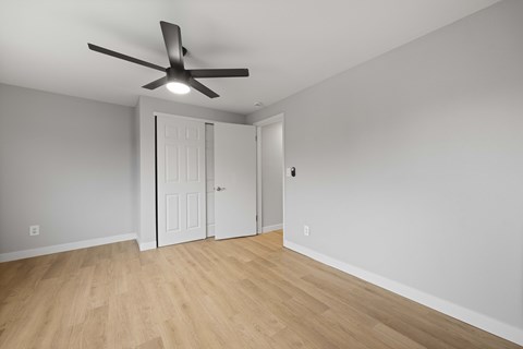 A room with a ceiling fan and wooden flooring.