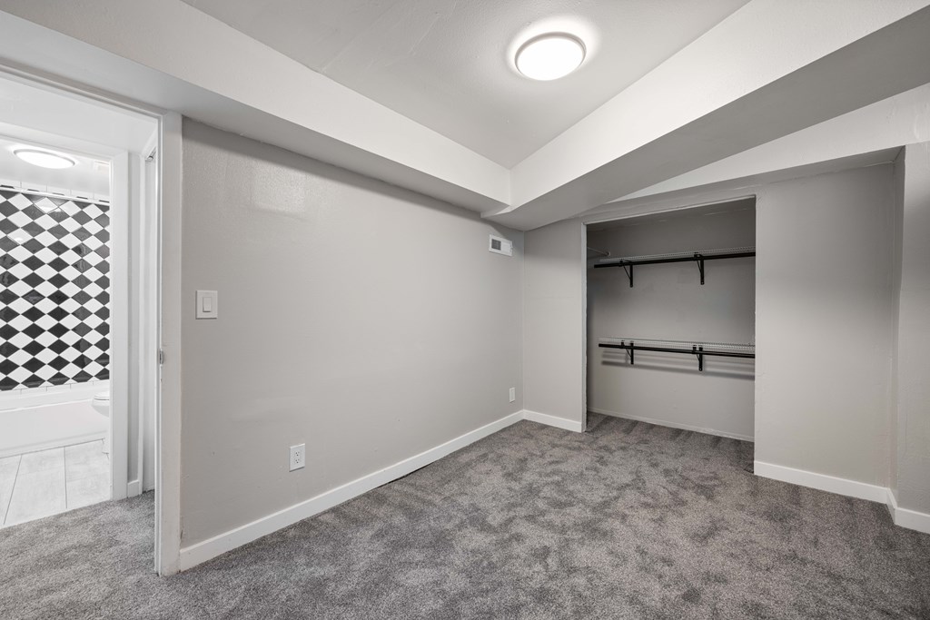 A spacious room with a checkered window and a grey carpet.
