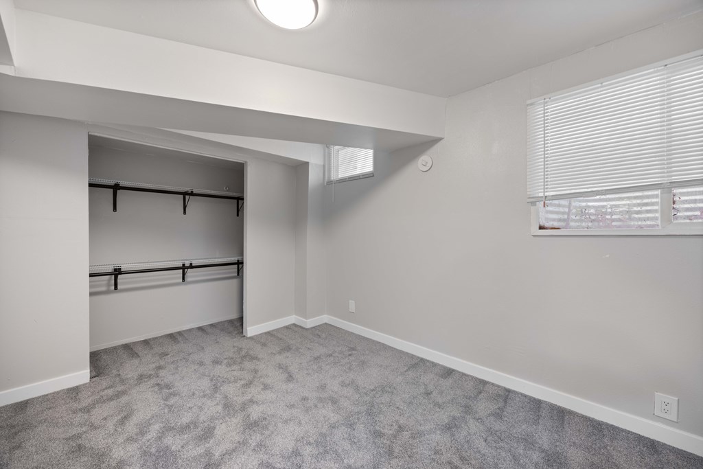 A room with a grey carpet and a white wall.
