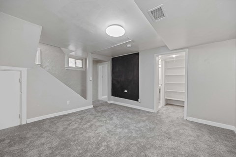 A spacious room with a staircase on the left and a blackboard on the right.