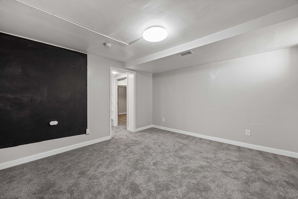 A room with a black chalkboard on the wall and a carpeted floor.