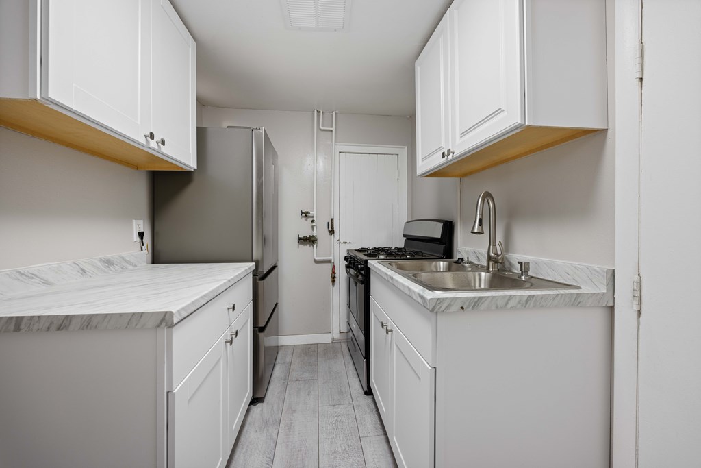 A kitchen with white cabinets and a marble countertop.