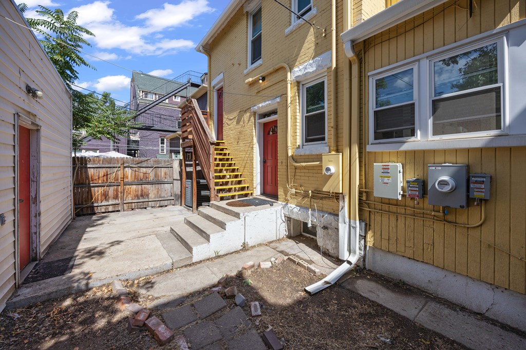 A yellow house with a red door and a small porch.