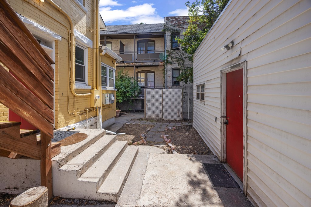 A red door is on the side of a white building.