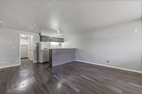 A kitchen with white appliances and a wooden floor.