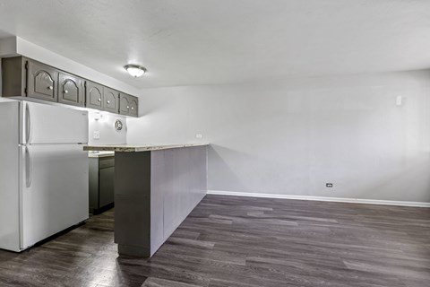 A kitchen with a white refrigerator and a wooden floor.