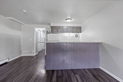 A room with a purple counter and wooden floors.