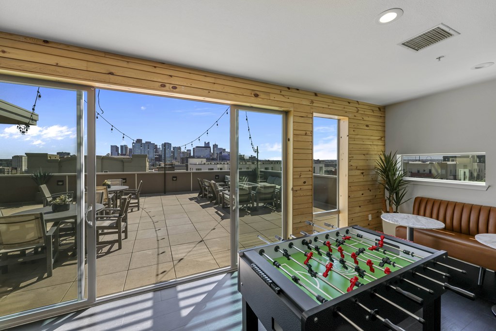 A foosball table is in the middle of a sunny room with sliding glass doors.