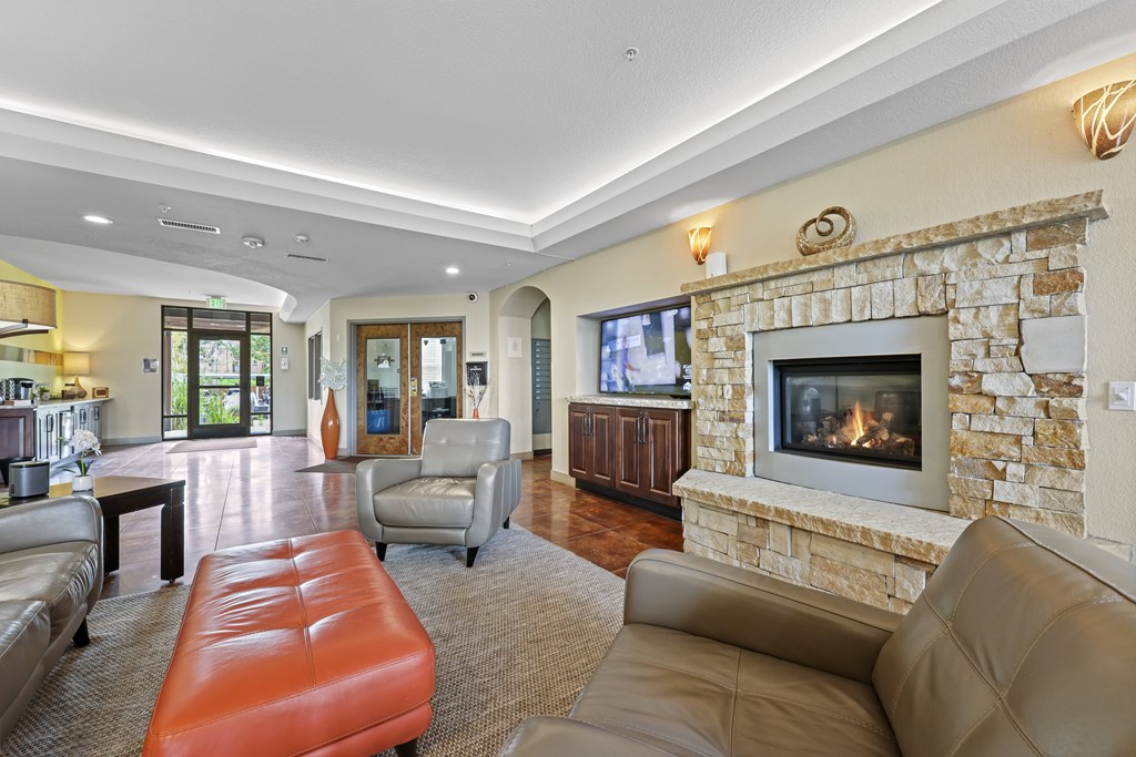 A living room with a stone fireplace and a flat screen TV.