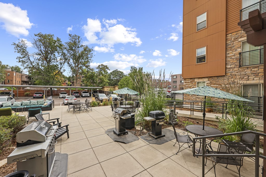 A patio with a grill and chairs.