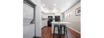 A kitchen with white appliances and black stools.