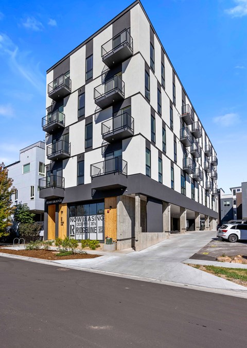 A modern apartment building with balconies on the second floor.