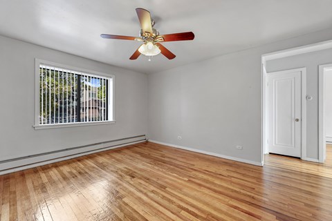 A room with a ceiling fan and a window with a view of trees.