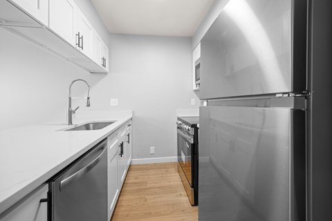 A modern kitchen with a stainless steel refrigerator and a white countertop.