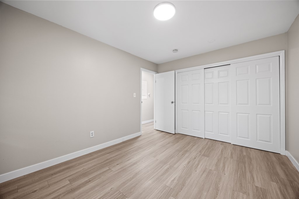 A room with a white door and wooden flooring.