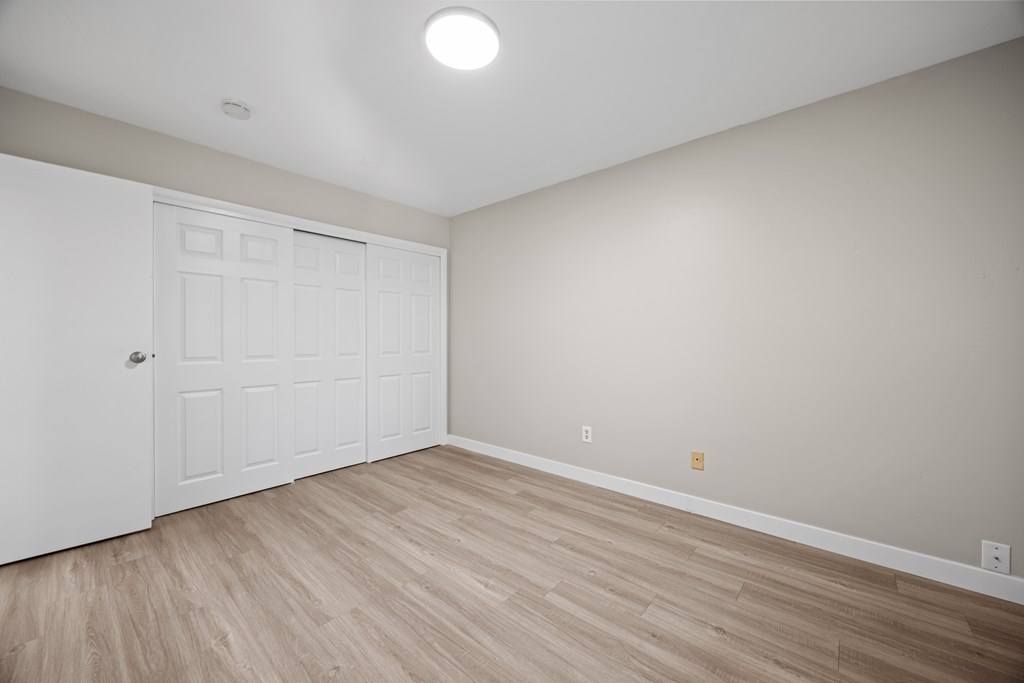 A room with a white door and wooden flooring.