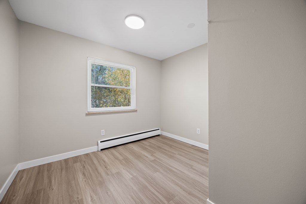 A room with a window and wooden flooring.