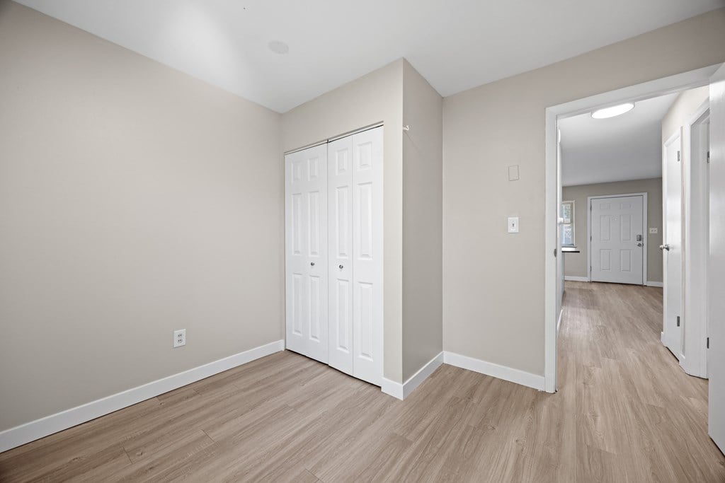 A room with a white door and wooden flooring.