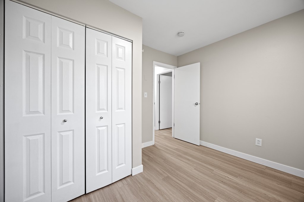 A hallway with two white doors and a wooden floor.