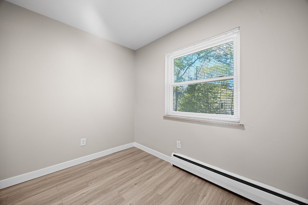 A room with a window and wooden flooring.