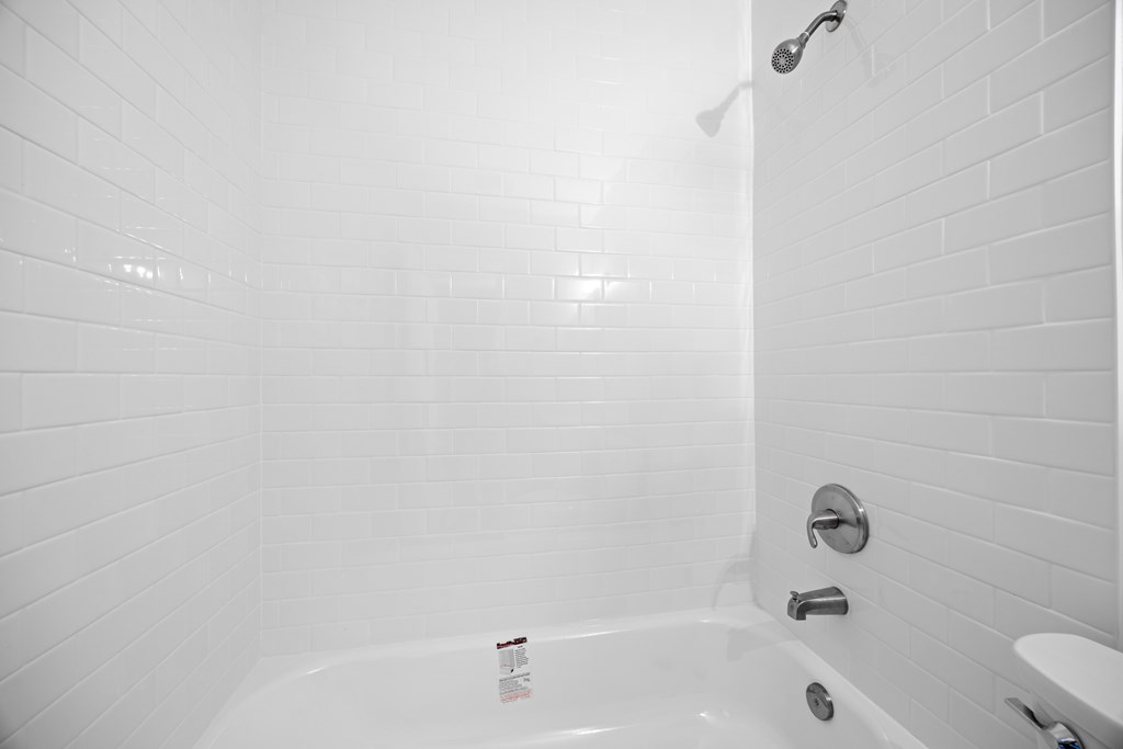 A white bathroom with a tub and a toilet.
