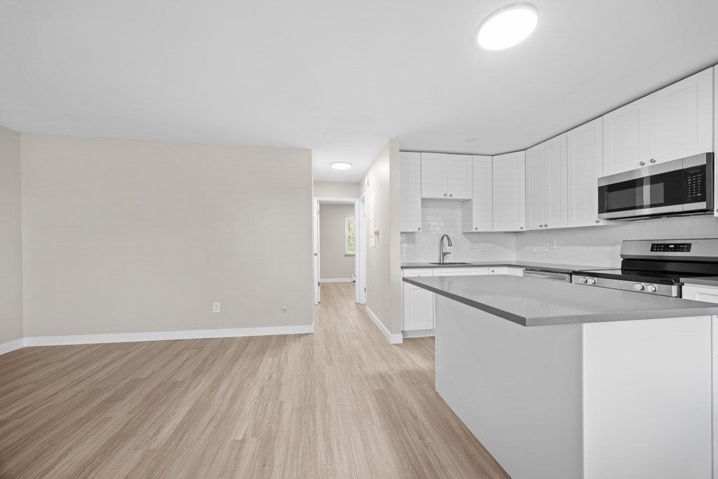 A kitchen with white cabinets and a wooden floor.