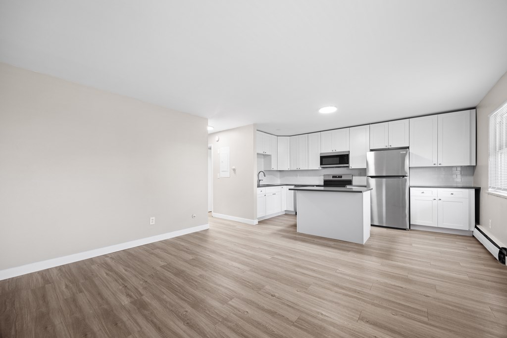 A kitchen with white cabinets and a wooden floor.