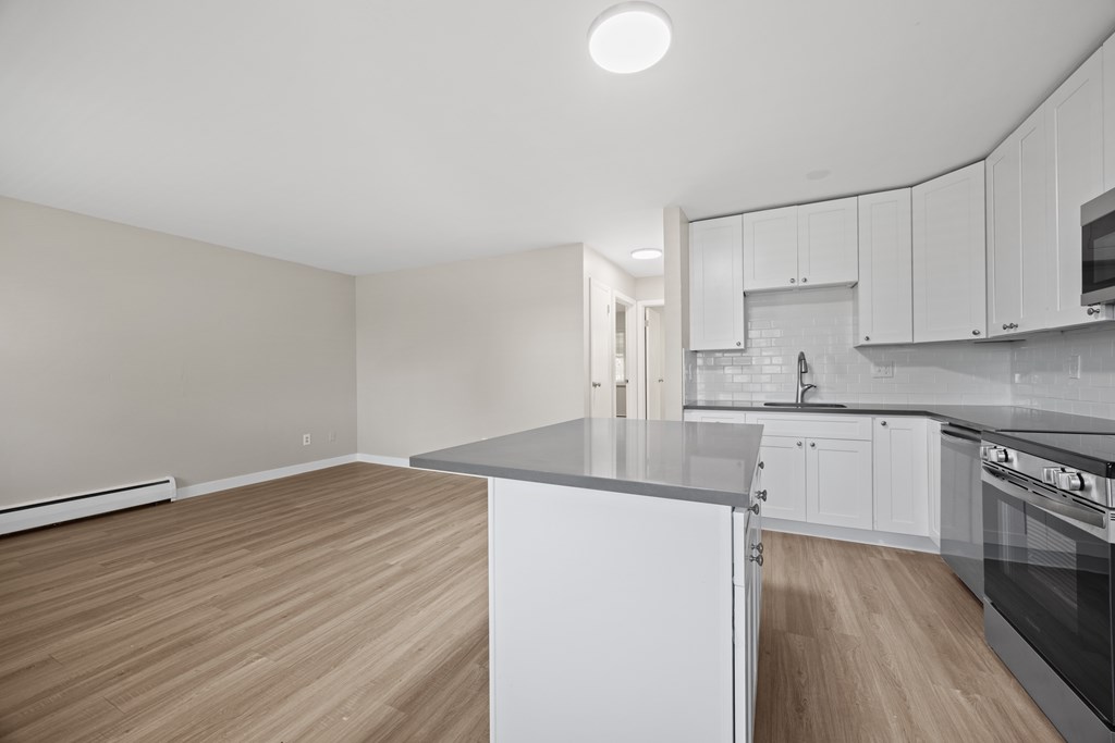 A kitchen with white cabinets and a wooden floor.