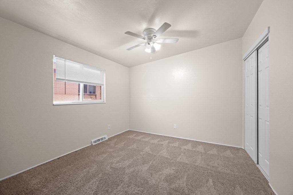 A room with a ceiling fan and carpeted floor.